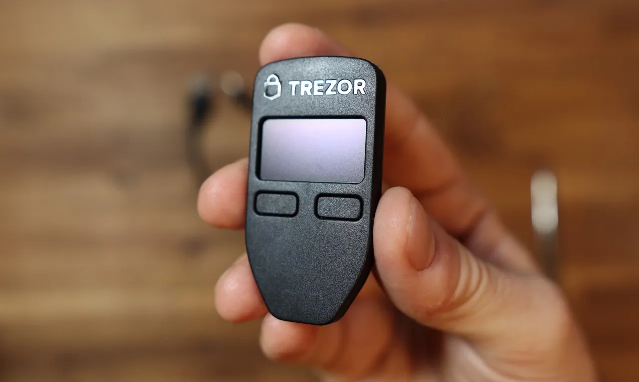 A classic black Trezor One hardware wallet showing the monochromatic OLED screen, representing the 1.6.1 firmware era of bitcoin nostalgia and early crypto security.